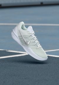 White athletic shoe with a textured mesh upper, silver Swoosh logo, and tonal laces. The sole is sleek and flat, designed for performance.