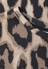 Gros plan sur un tissu à motif animalier noir et gris avec un col rond cousu.