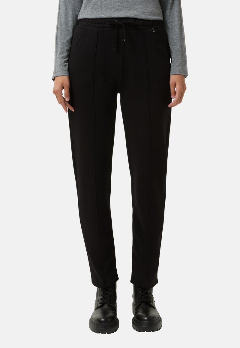 Zwarte joggingsbroek met een aantrekkoord in de taille, voorzien van zijzakken en gestikte details voor textuur. G gedragen met zwarte veterschoenen.