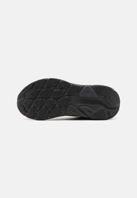 Semelle de chaussure en caoutchouc noir avec une surface texturée, dotée de crampons multidirectionnels pour l'adhérence et d'une forme élégante et définie.