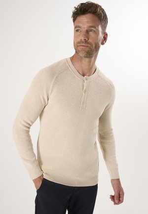 Beige ribbed long-sleeve henley shirt with a rounded neckline and three-button placket. Soft texture with fitted sleeves and hem.