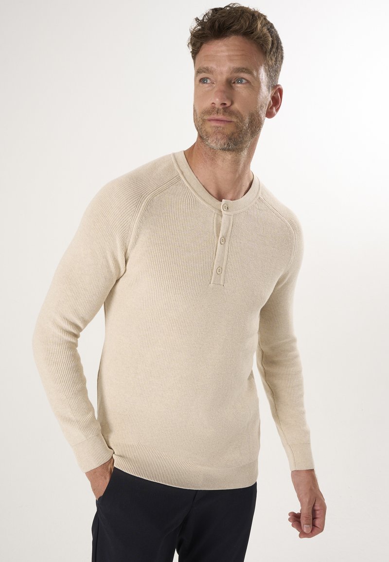 Beige geripptes Langarm-Henley-Shirt mit rundem Ausschnitt und Drei-Knopf-Leiste. Weiche Textur mit eng anliegenden Ärmeln und Saum.