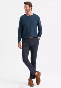 Maglione blu navy con texture abbinato a pantaloni grigi a quadri. Stivali in pelle scamosciata marroni. Design semplice con vestibilità comoda e senza motivi visibili.
