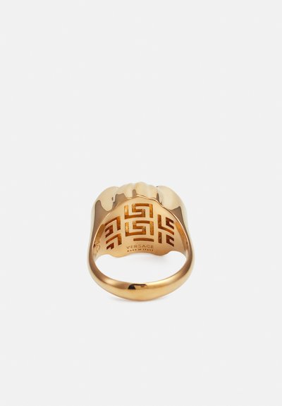 Zlatom pozlátený prsteň s odvážnym dizajnom, textúrovaným povrchom a zložitým vnútorným vzorom, s pečaťou "Versace Made in Italy."