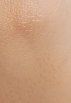 Gros plan de peau lisse et de ton clair montrant la texture naturelle et les fines lignes.