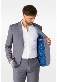 Grau Anzugjacke mit Reverskragen und zwei Knöpfen, ausgestattet mit einem lebhaften blauen gemusterten Futter mit orangefarbenen Akzenten. Darunter ein weißes Hemd.