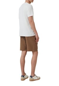 T-shirt en coton blanc, shorts en velours côtelé marron et baskets blanches avec des accents navy, vus de dos. Design simple et décontracté.