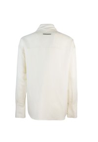 Camicia a maniche lunghe color crema realizzata in tessuto morbido, con una spalla posteriore e un'etichetta al collo con il marchio "PATRIZIA PEPE".