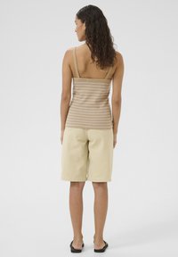 Tan-striped tank top with wide straps, paired with light beige shorts. The material looks soft, featuring a relaxed fit and knee-length shorts.