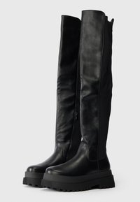 Botas pretas acima do joelho com frente em couro liso, parte traseira em tecido, sola espessa e plataforma, além de fecho lateral para fácil acesso.