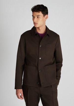 Chaqueta de trabajo marrón con cuello, botones frontales y dos bolsillos de parche. La tela tiene textura y el diseño incluye detalles sutiles.