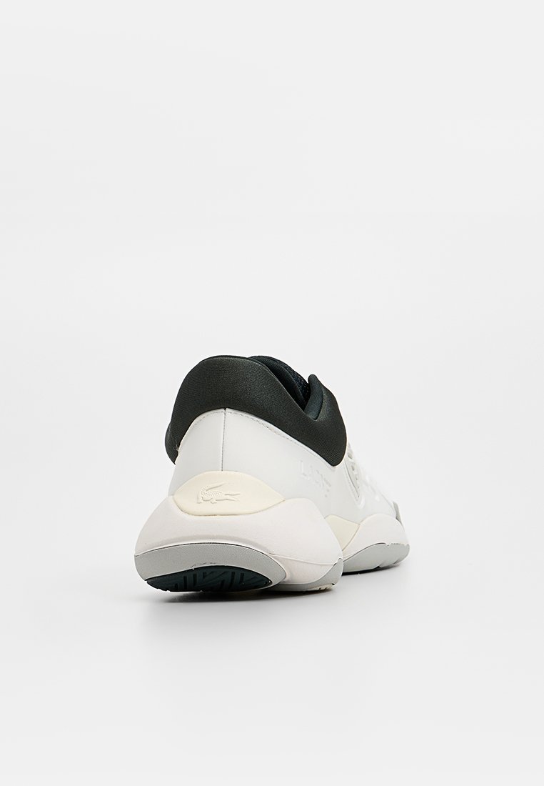 Lacoste sneakers with a white and black color scheme, textured material, round shape, cushioned heel, and subtle branding detail.