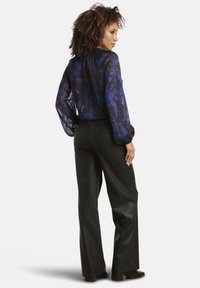 Sheer black blouse with blue floral pattern, puffed sleeves, and a gathered neckline; paired with high-waisted black leather pants.