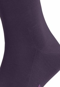 Lila Kompressionssocke mit strukturiertem Rippdesign, glatter Oberfläche und dezentem Branding nahe dem Bündchen. Leichtes, anliegendes Design.
