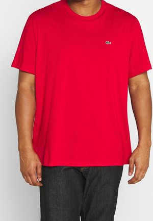 T-shirt rossa in cotone con scollo a girocollo, maniche corte e un piccolo logo verde sul lato sinistro del petto. Texture liscia. Vestibilità standard.