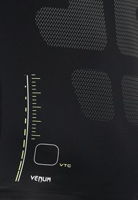 Camisa atlética negra con paneles de malla texturizada, con acentos en blanco y verde neón, y un diseño gráfico para la marca.