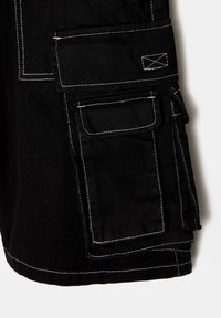 Short cargo noir avec de grandes poches rectangulaires et des surpiqûres blanches contrastantes sur les coutures et les bords des poches.