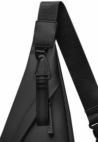 Borsa a tracolla nera con una finitura liscia e testurizzata, dotata di una larga tracolla in nylon e ferri metallici per un attacco sicuro.