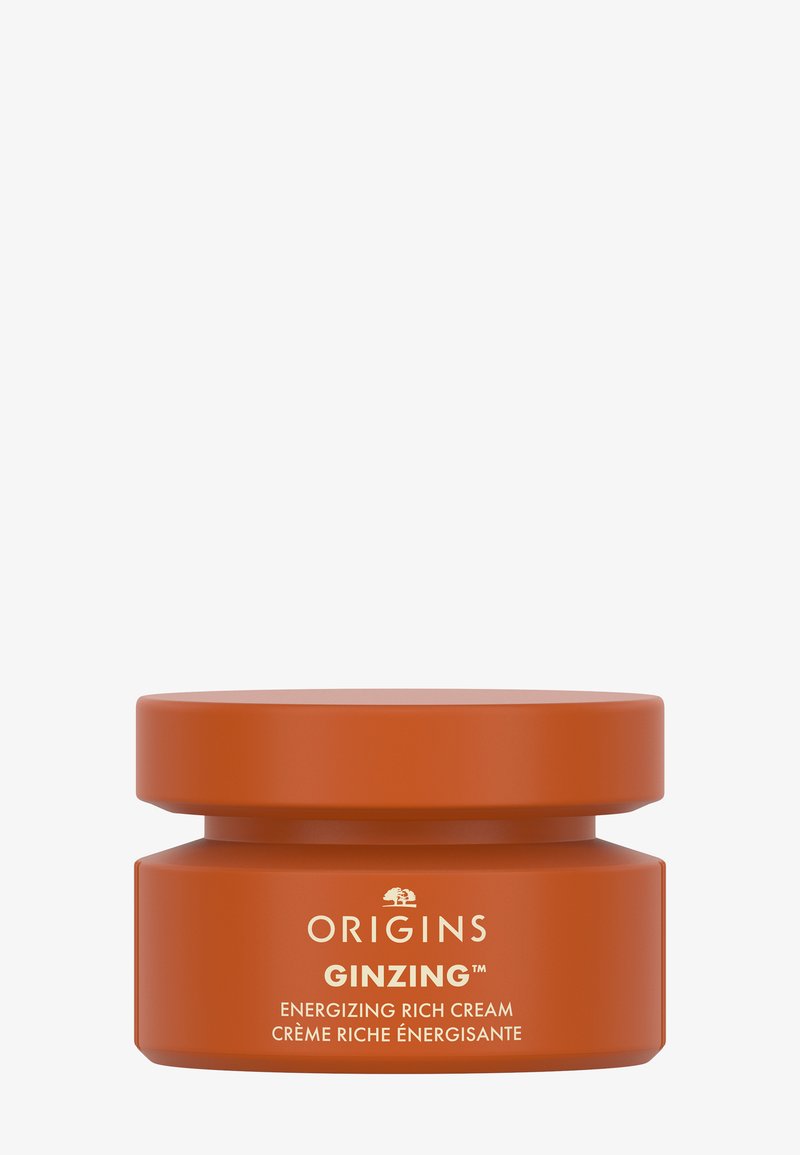 Oranje pot met een matte afwerking, voorzien van een vlak deksel en witte tekst. Etiket zegt "Origins Ginzing Energizing Rich Cream."