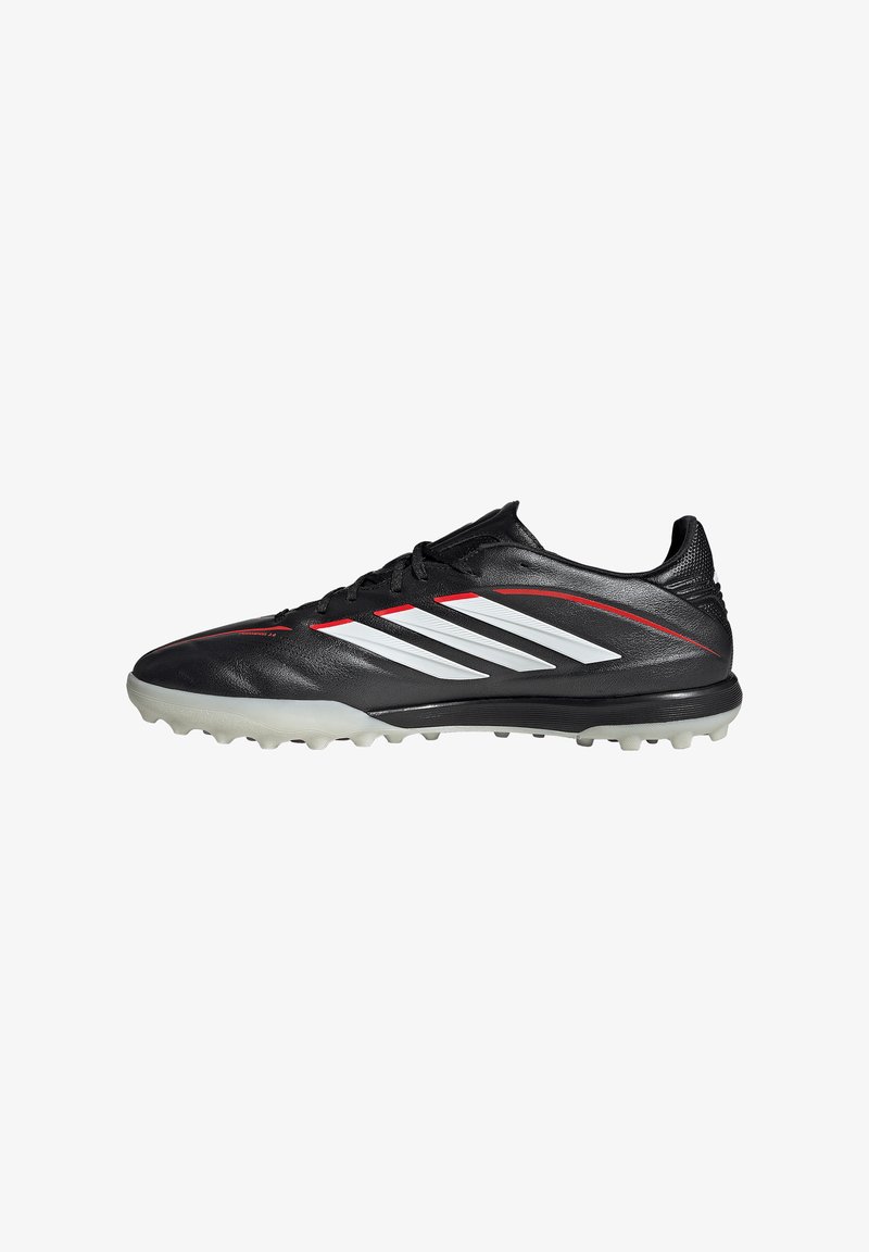 Crampon de football noir avec des bandes blanches Adidas, des lignes d'accent rouges et une semelle cloutée gris clair, présenté en profil latéral.