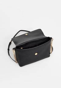 Borsa a tracolla in pelle nera strutturata con una catenina in metallo dorato, patta superiore e tasca interna con zip.