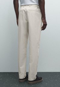 Pantaloni beige realizzati in tessuto leggero, con vestibilità dritta, vita elastica, tasche laterali e tasche posteriori a filetto.