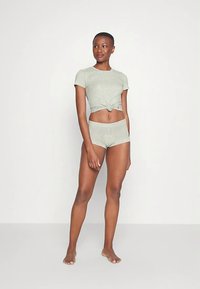 Pilkas, mazgas priekyje susietas trumpomis rankovėmis viršus kartu su derančiais aukšto liemens šortais, pagamintas iš minkštos medžiagos ir turintis laisvą siluetą.