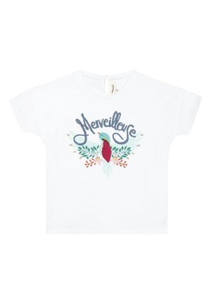 Camicia bianca a maniche corte con uccello blu ricamato circondato da foglie e fiori, e la parola "Merveilleuse" sopra l'uccello.