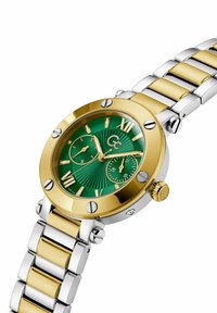 Orologio in metallo dorato e argentato con quadrante verde testurizzato, dotato di indicatori delle ore dorati, sottodial e una lunetta dorata con accenti argentati.