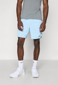 Light blue athletic shorts with textured design, worn with a gray shirt and white sneakers. Nike logo on shorts and socks.