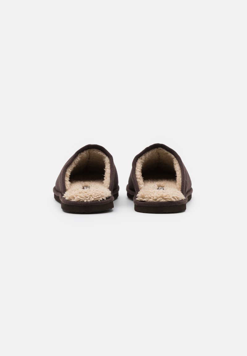 Zapatillas de tela marrón con un suave forro de piel sintética beige y diseño de parte trasera abierta. Suelas planas y construcción sencilla para un uso fácil y cómodo.