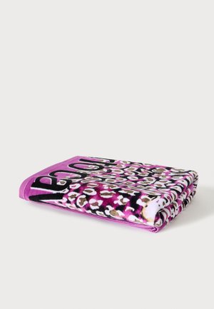 Toalla de playa rosa doblada con estampado de leopardo en negro, blanco y marrón y texto grande en negro en un borde.