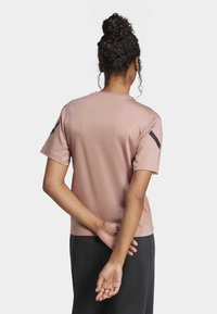 Camiseta deportiva de manga corta, de color rosa claro, con cuello redondo y detalles en negro en las mangas. Confeccionada en tela suave y ligera.