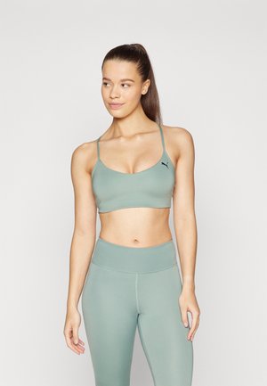 Soutien-gorge de sport vert clair avec des fines bretelles et un col arrondi, associé à un legging taille haute assorti, fabriqué à partir d'un matériau lisse et extensible.