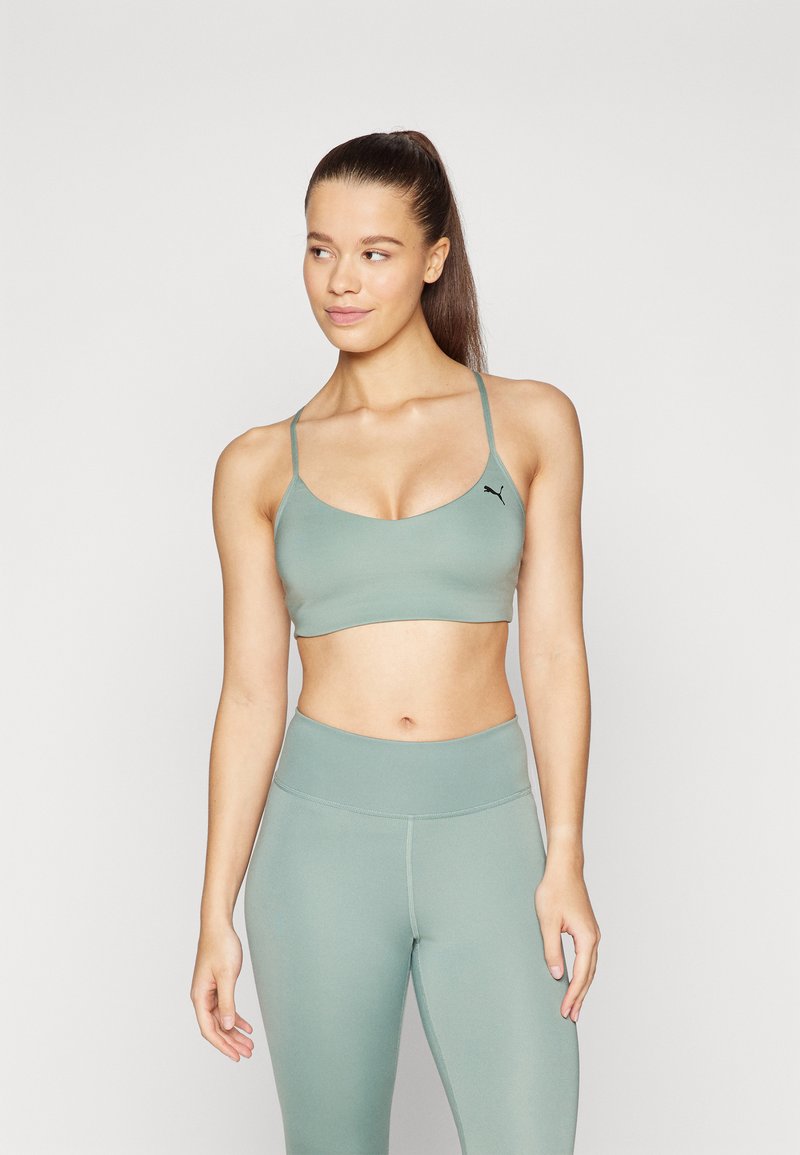 Lys grøn sports-BH med tynde stropper og rund udskæring, parret med matchende højtaljede leggings lavet af glat, strækbart materiale.