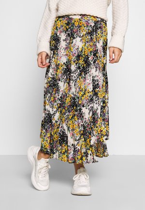 Middelgrote rok met bloemmotief en plooien in crème, met zwarte, gele en paarse bloemen; gecombineerd met witte sneakers en een textuurtrui.