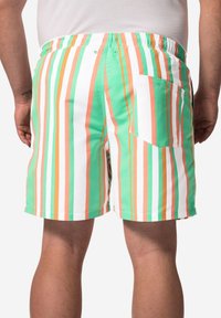 Mångfärgad simbyxa med vertikala ränder i grönt, orange och vitt. Resårmidja med en bakficka för förvaring.