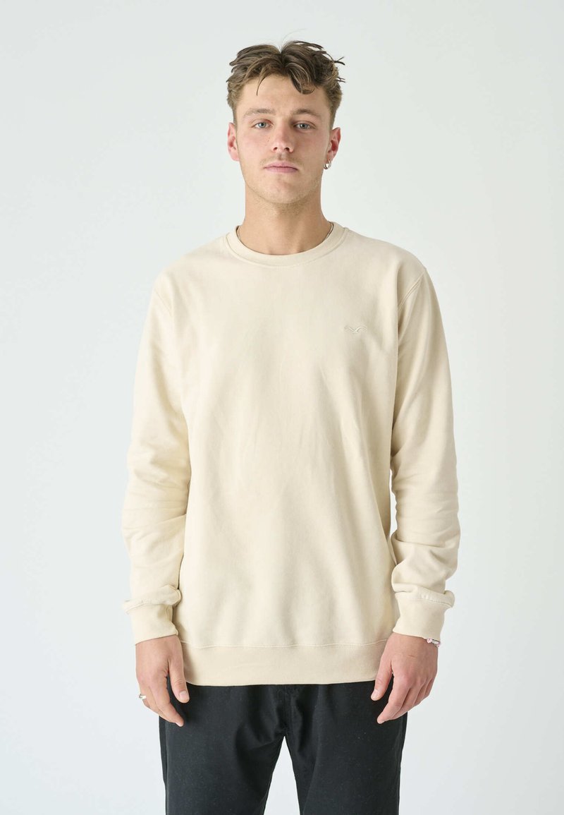 Beige long-sleeve sweatshirt made of soft fabric, featuring a crew neck, ribbed cuffs, and a subtle logo on the chest.
