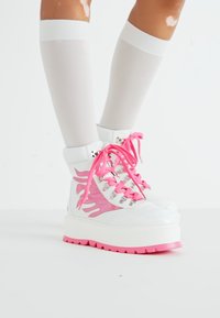 Witte hoge sneakers met roze vlamaccenten en levendige roze veters. Dikke witte zool met een roze onderzijde. Gladde, glanzende afwerking.