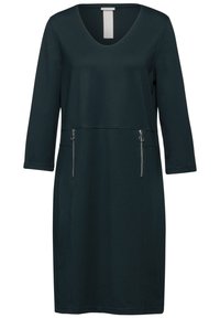 Robe vert foncé en tissu doux, dotée d'un décolleté en V, de manches trois-quarts et de deux poches zippées à l'avant.