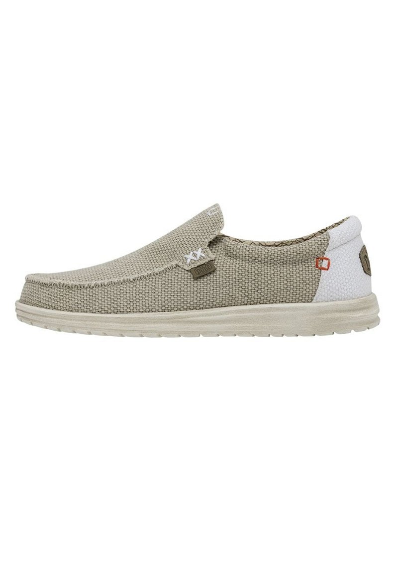 Des chaussures slip-on beige avec un dessus tissé texturé, une semelle gris clair et une section de talon blanche contrastante. Présente un branding minimal et des détails de couture.