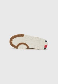 Semelle en caoutchouc marron avec motif de semelle texturé et intersemelle blanche. Présente des accents rouges et navy au niveau du talon. Profil plat, conçu pour l'adhérence.