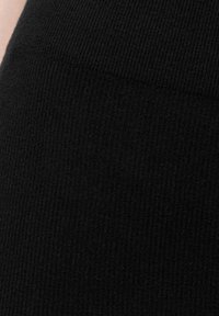 Tessuto a coste nero che presenta una superficie liscia e un motivo di maglia continua. La composizione enfatizza calore e elasticità.