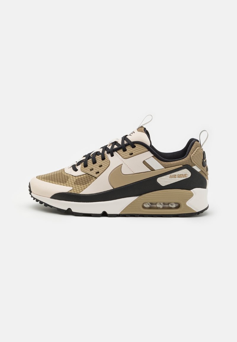 Basket Nike Air Max beige, marron, noir et blanc avec semelle à coussin d'air visible et lacets noirs.