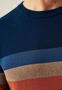Pull en maille bleu marine avec des rayures horizontales en bleu clair, beige et rouille. Doté d'un col ras du cou côtelé et d'une texture douce.