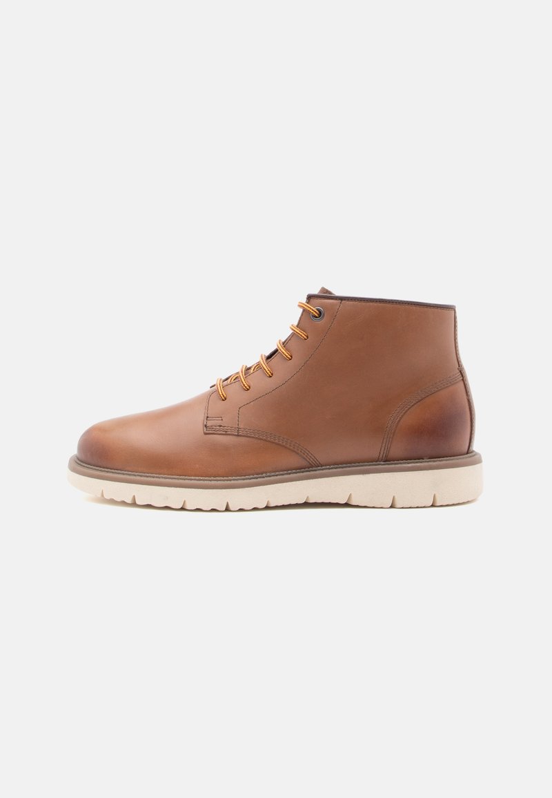 Botas de cuero marrón hasta el tobillo con puntera redonda, cordones de seis ojales, acentos en naranja y una suela de goma beige clara con dibujo texturizado.