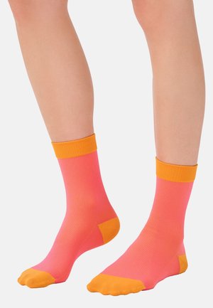 Helle rosa Socken mit orangefarbenen Rippbündchen und Zehenakzenten. Hergestellt aus einem glatten, dehnbaren Material mit engem Sitz.