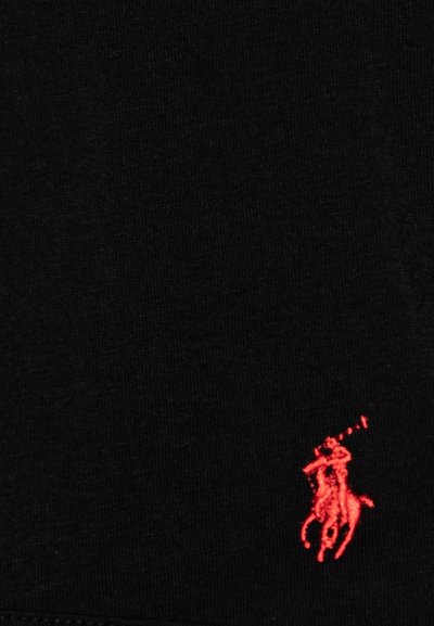 Tejido negro con una superficie texturada y un pequeño logotipo bordado en rojo de un jugador de polo montando un caballo en la esquina inferior derecha.
