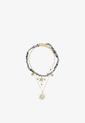 Layered gold-tone necklaces with a black and white patterned fabric cord and sun, starfish, and shell-shaped charms.