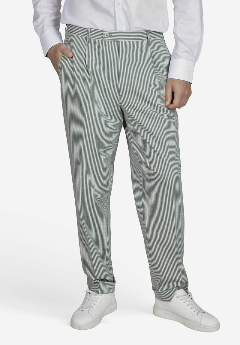 Groen en witte gestreepte broeken met een relaxed fit, met plooien aan de voorkant en gedragen met witte sneakers. Gladde stoftextuur.